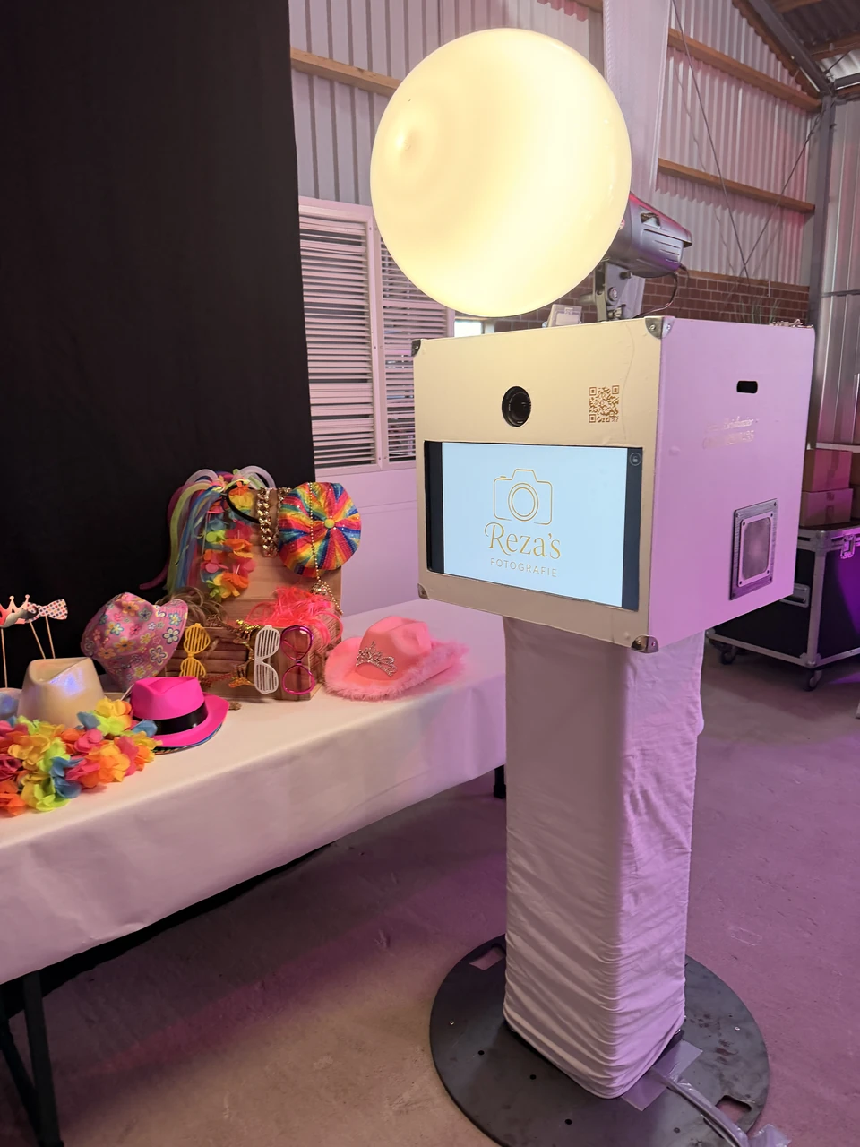 Rezas Fotobox bei einer Feier mit eigenem Logo auf dem Bildschirm und bunten Accessoires