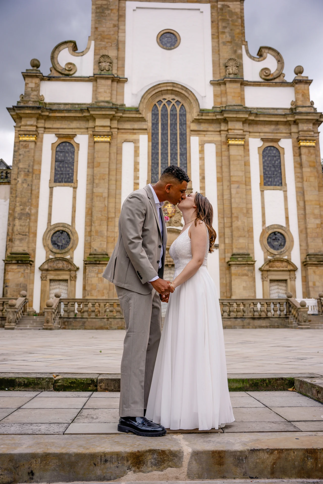 Brautpaar küsst sich vor der Kirche – Hochzeitsfotografie von Reza